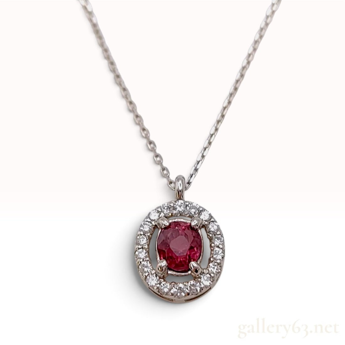 Pt900 and Pt850 Platinum 0.445ct Red Spinel and 0.11ctw Diamond Necklace with Certificate: A platinum pendant necklace featuring a central natural red spinel in an oval mixed cut weighing 0.445ct. The gemstone is held in a four-prong setting within a circular halo of small round brilliant-c