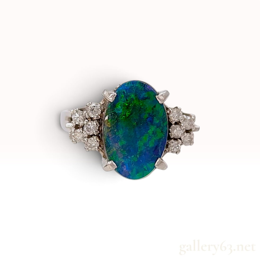 Platinum 2.14ct Boulder Opal and 0.23ctw Natural Diamond Cocktail Ring: This platinum cocktail ring is centered on a 2.14ct oval cabochon boulder opal. The opal displays an intense play-of-color with vibrant electric green and deep blue flashes against a dark ground, with