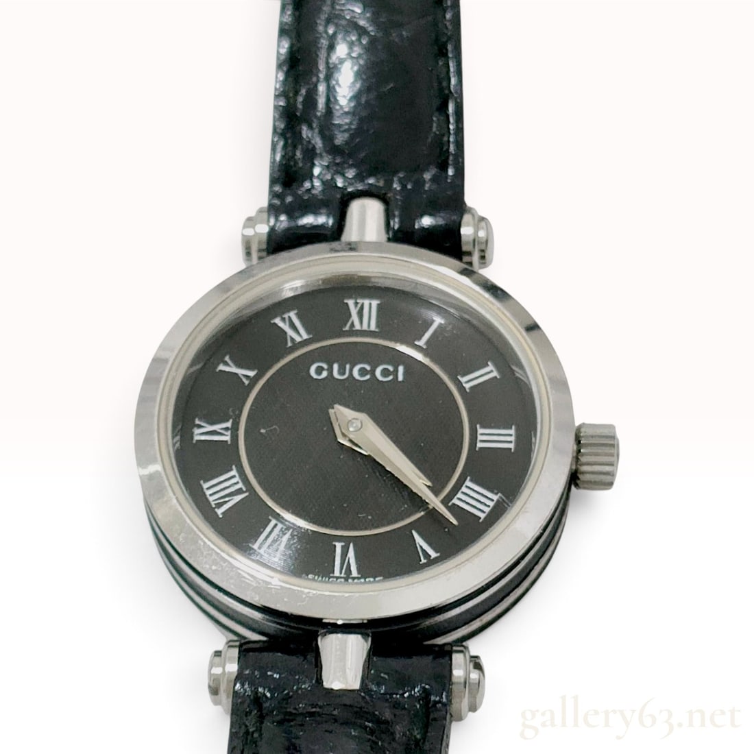 Vintage Gucci 2040L Black Dial Stainless Steel Ladies Watch: This Gucci ladies wristwatch is a model 2040L featuring a tiered stainless steel case with black enameled sides. The black dial is accented by an outer ring with silver Roman numeral hour markers and 