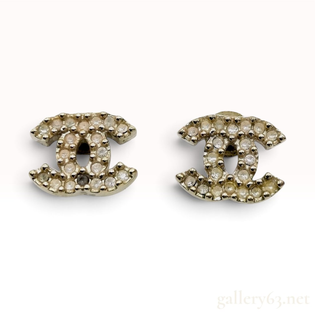 c. 2010 Chanel Crystal CC Stud Earrings, Gold-Tone: A pair of Chanel stud earrings crafted from gold-tone metal, designed in the form of the signature interlocking CC logo. The earrings feature a textured pave-style setting with circular clear crystals
