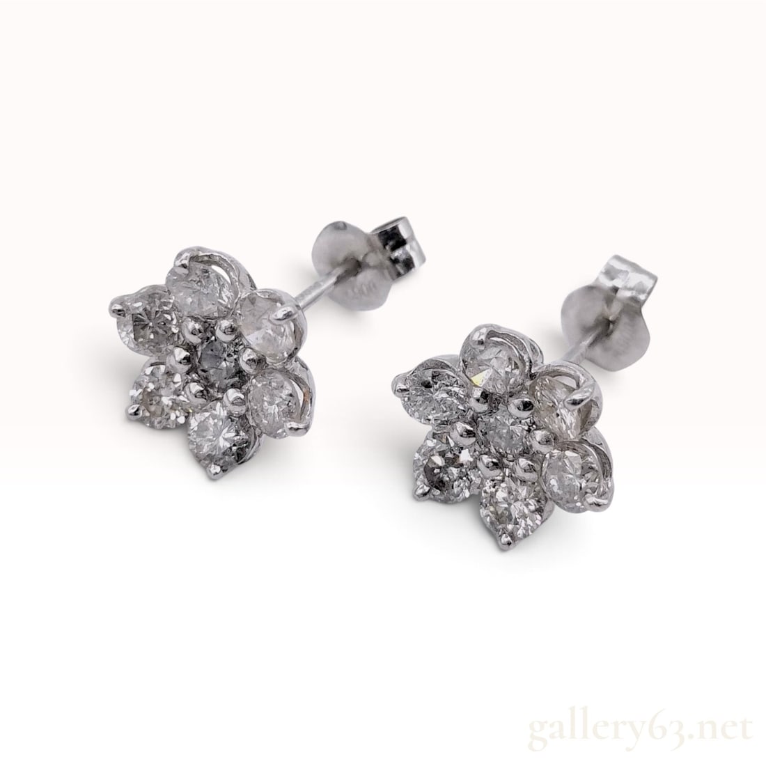 1.00ctw Natural Diamond Platinum Floral Cluster Stud Earrings: A matched pair of platinum and natural diamond stud earrings, each designed as a seven-stone floral cluster. Each earring features a central round brilliant cut natural diamond surrounded by six round