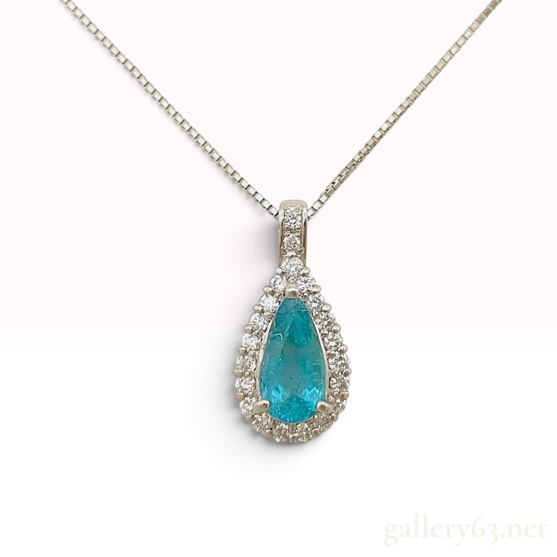 An Important 1.494ct Paraiba Tourmaline and 0.37ctw Natural Diamond Pendant Necklace in Platinum: This platinum pendant necklace features a central pear-cut Paraiba tourmaline weighing 1.494ct. The stone exhibits a transparent blue-green color and is secured by four prongs within a halo of round b