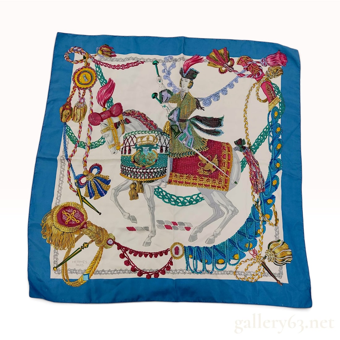 Vintage Hermes Blue Equestrian Motif Silk Carre 90: This Hermes silk carre 90 is composed of silk twill and features an elaborate equestrian design. The central scene illustrates a timpanist in dress uniform mounted on a white horse, positioned between