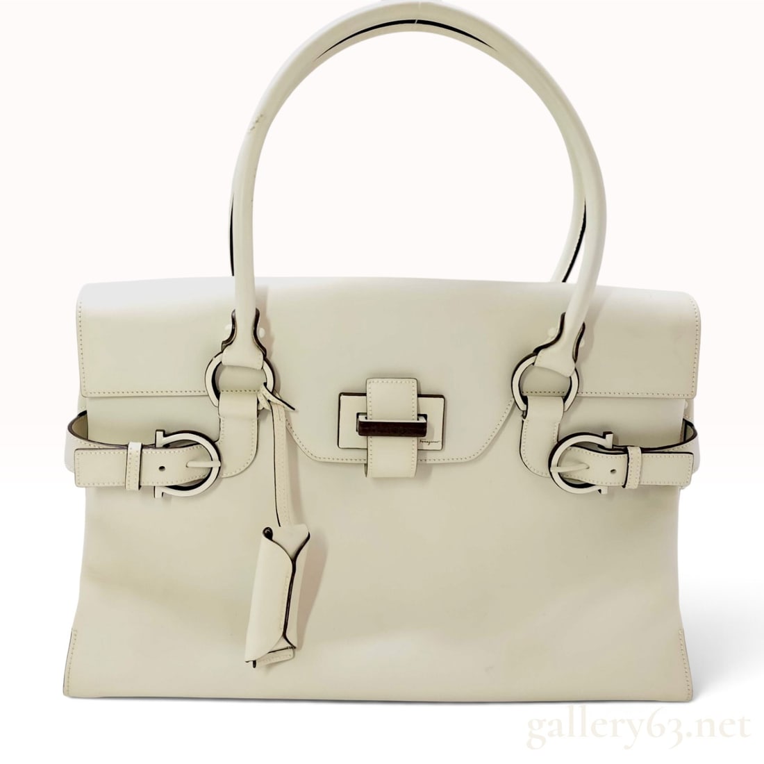 Salvatore Ferragamo Gancini Cream Leather Satchel with Wood Hardware: This Salvatore Ferragamo satchel is crafted from smooth cream leather with a structured rectangular silhouette. The exterior features double rolled leather top handles secured to dark wood Gancini rin