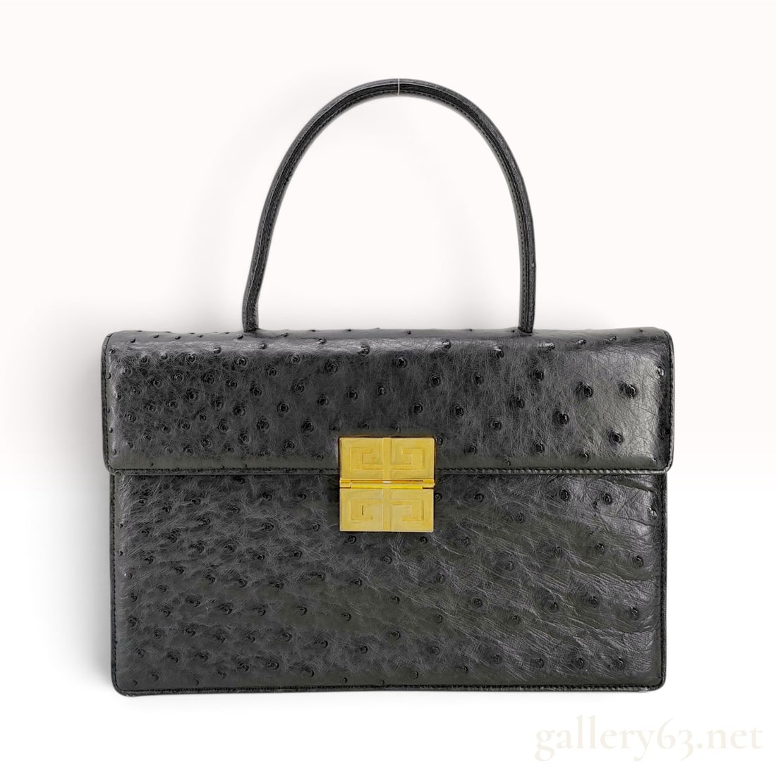 Vintage Givenchy Black Ostrich Leather Top Handle Bag: This is a vintage Givenchy top handle bag crafted from black ostrich leather. The structured silhouette features a single rounded handle and a front flap closure with a square gold-tone clasp displayi