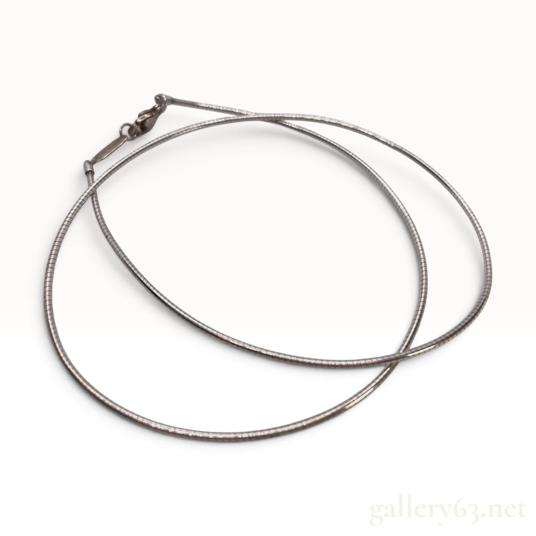 Tiffany & Co. Sterling Silver Snake Chain Necklace: This Tiffany & Co. necklace is crafted from sterling silver in a round snake chain style. The chain consists of closely linked, rounded silver segments that provide a smooth, flexible texture. It is s