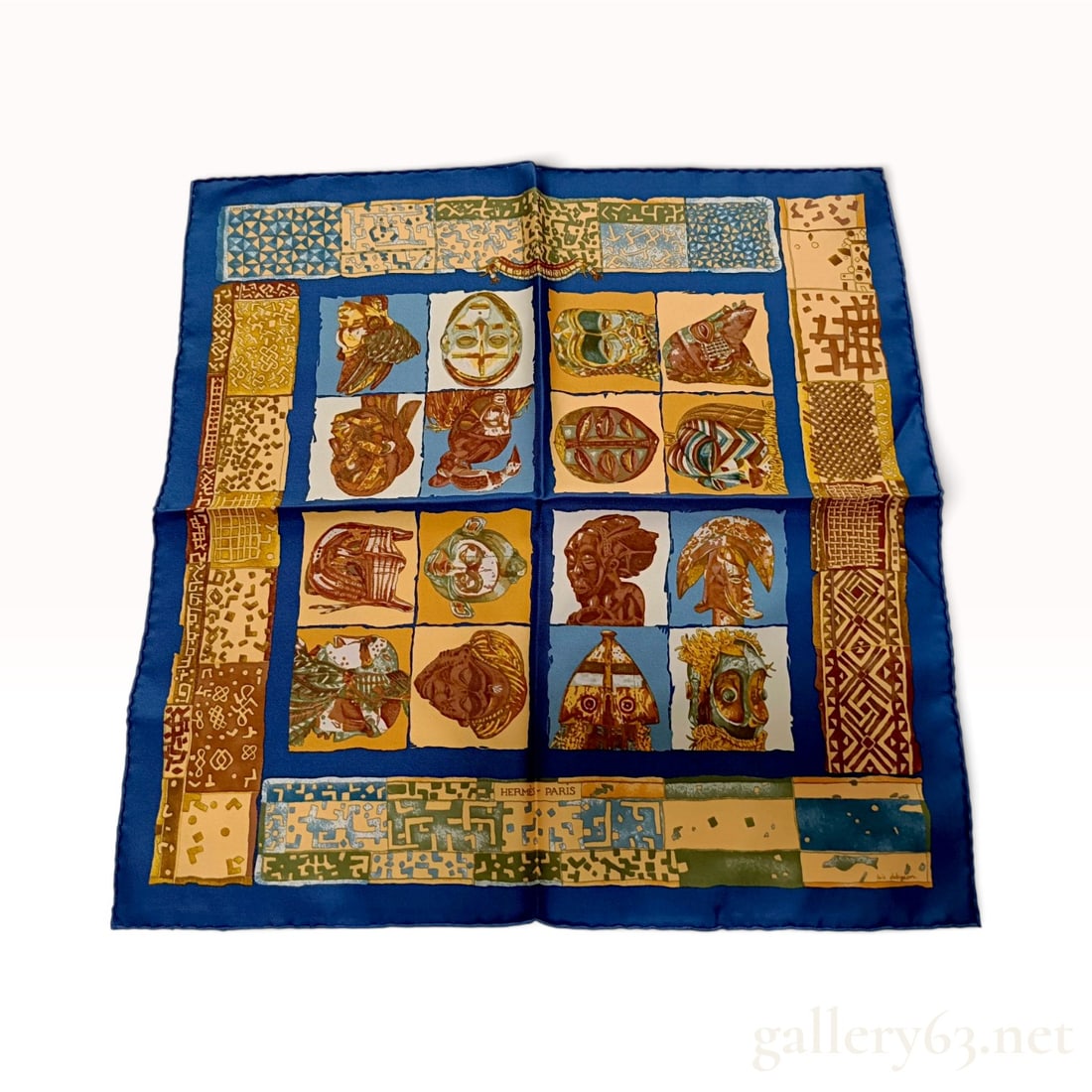 Vintage Hermes Persona Blue Silk Carre 45: A vintage Hermes silk carre 45 in the Persona pattern designed by Loic Dubigeon. The design depicts sixteen diverse ethnographic masks arranged in a grid, surrounded by a complex border of various geo