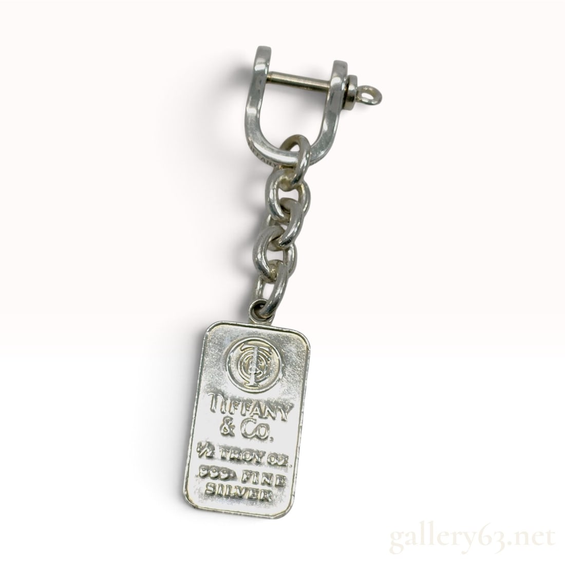A Vintage Tiffany & Co. 1/2 Troy Oz Fine Silver Ingot Keychain with Box: A Tiffany & Co. bullion-style keychain featuring a rectangular ingot charm suspended from a three-link oval chain and shackle-style clasp. The charm is struck from 0.50 troy ounces of .999 fine silver