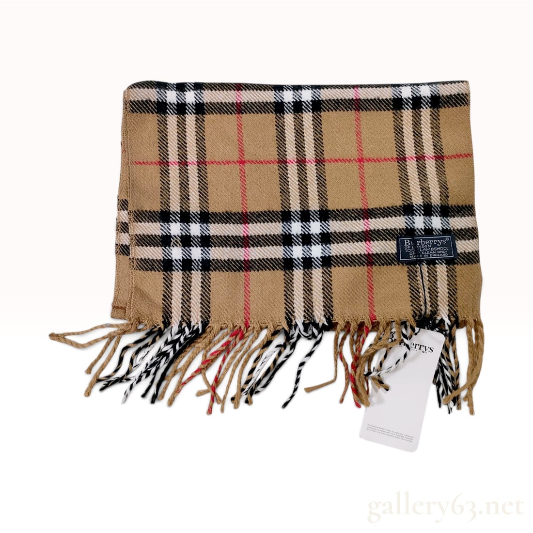 Vintage Burberrys Nova Check Beige Lambswool Scarf NWT: This Burberrys scarf is crafted from 100% lambswool in the signature beige Nova Check pattern, featuring intersecting stripes of black, white, and red. The scarf is finished with a twisted fringe alon