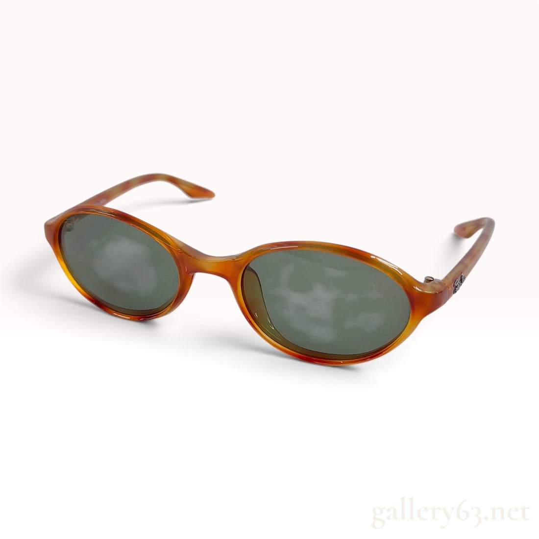 Vintage Ray-Ban W2834 Amber Tortoiseshell Acetate Oval Sunglasses with Pouch: This pair of vintage Ray-Ban W2834 sunglasses is crafted with amber tortoiseshell-patterned acetate frames in an oval silhouette. The eyewear is fitted with green-tinted glass lenses and standard meta