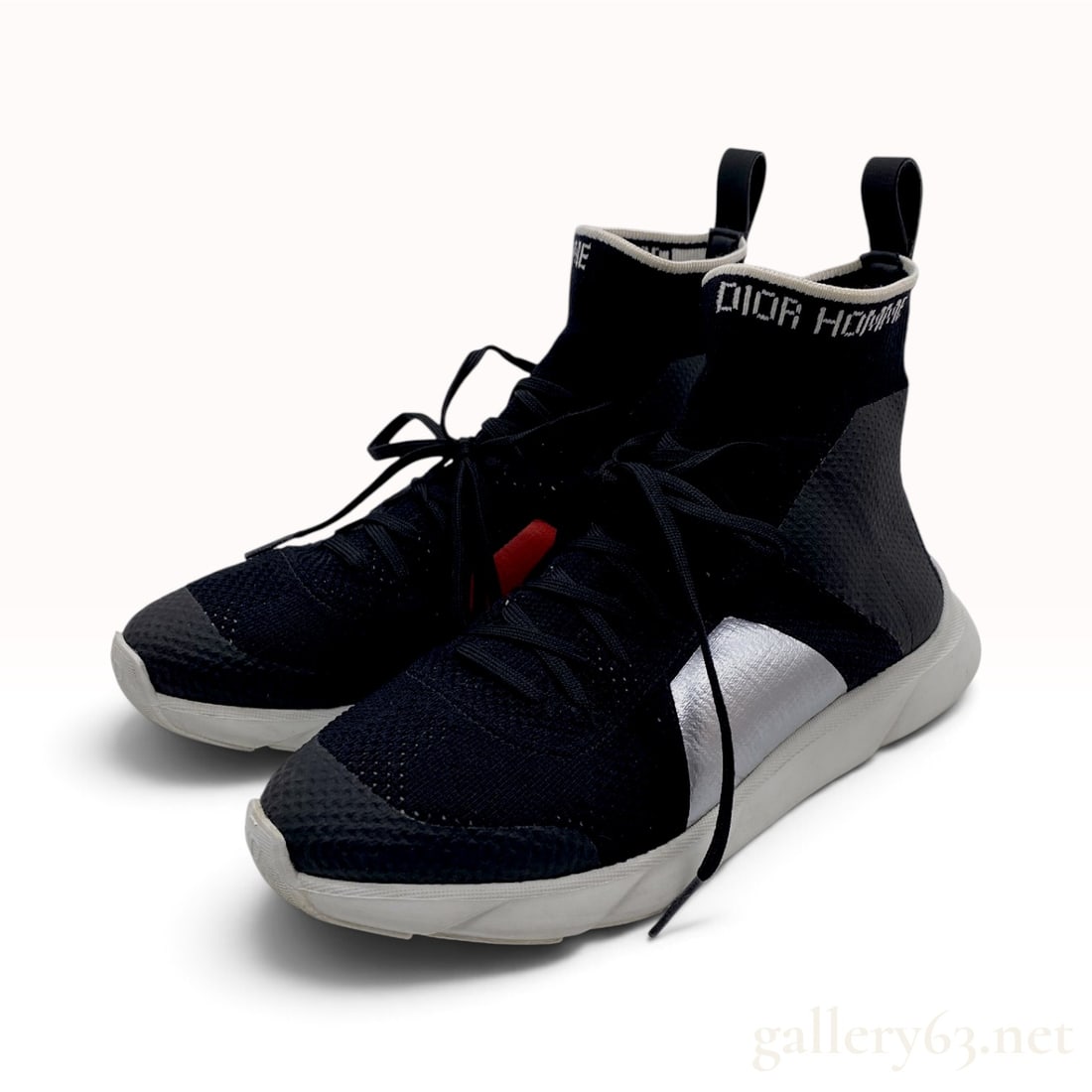 Dior Homme B21 Black and Silver Technical Knit High-Top Sneakers: This pair of Dior Homme B21 high-top sock sneakers is crafted from black technical knit with silver metallic synthetic overlays. The design features a white knit DIOR HOMME identifier at the ankle col