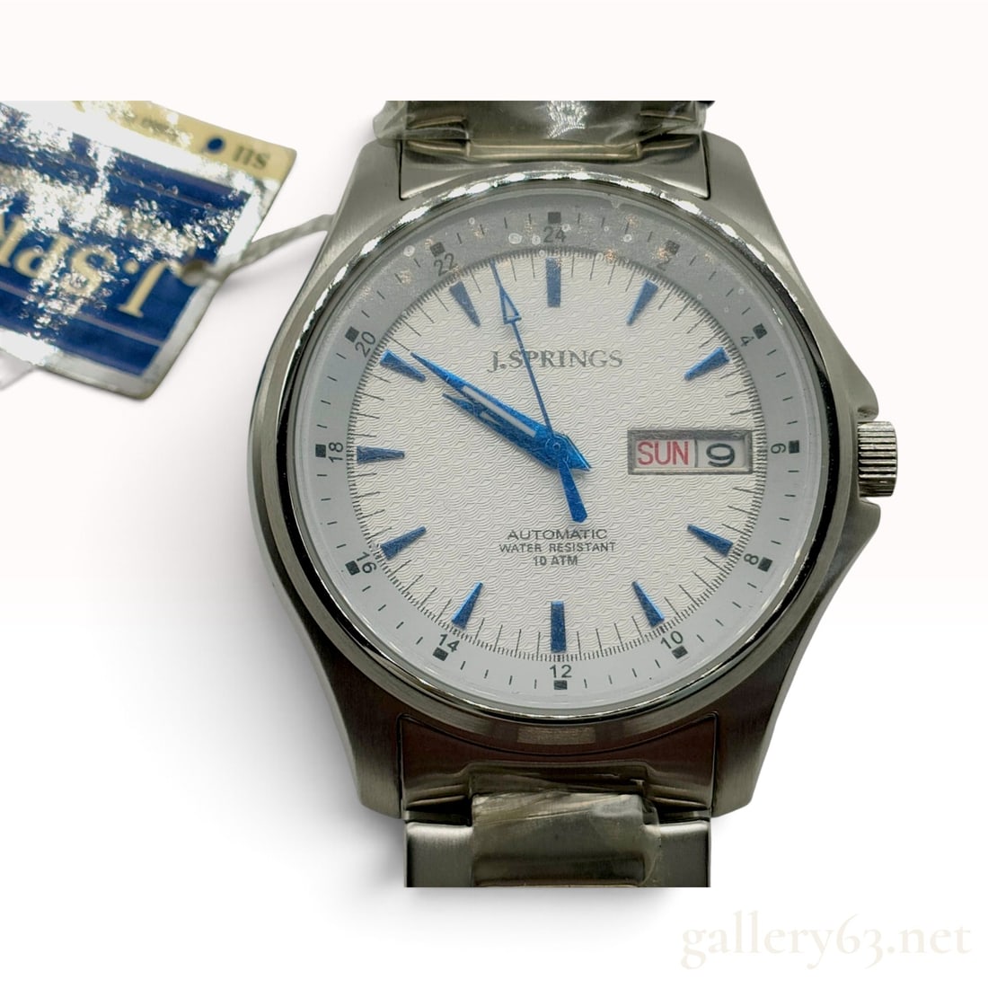 J. Springs Automatic BEB014 White Wave Dial Stainless Steel Wristwatch with Tags: This J. Springs automatic wristwatch, reference BEB014, is constructed with a brushed and polished stainless steel case and a matching integrated link bracelet. The textured white dial features a repe