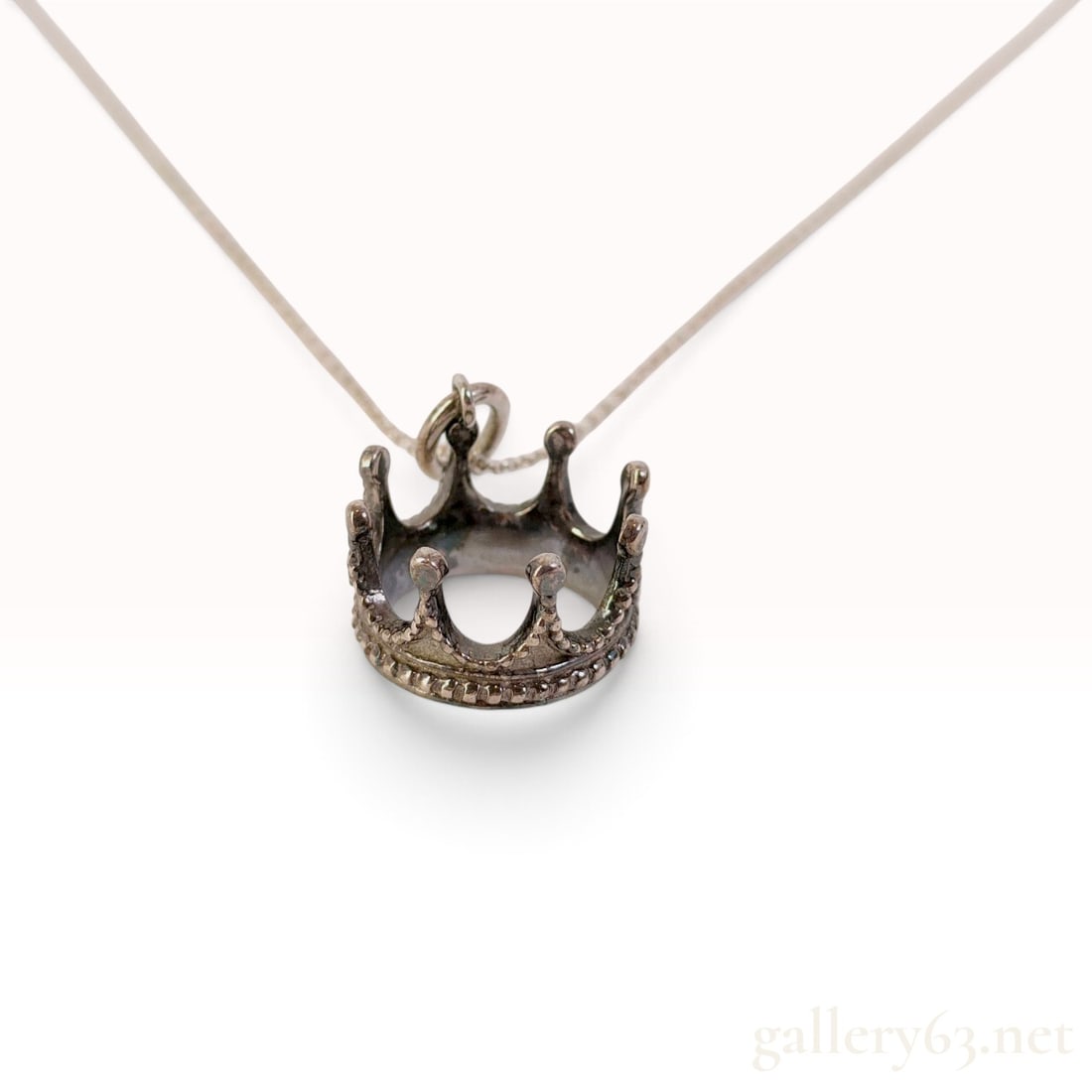 Tiffany & Co. Crown Sterling Silver Pendant Necklace: This Tiffany & Co. crown pendant necklace is crafted from sterling silver. The dimensional pendant is designed as a royal crown, characterized by a circular base with beaded edging and arches ending i
