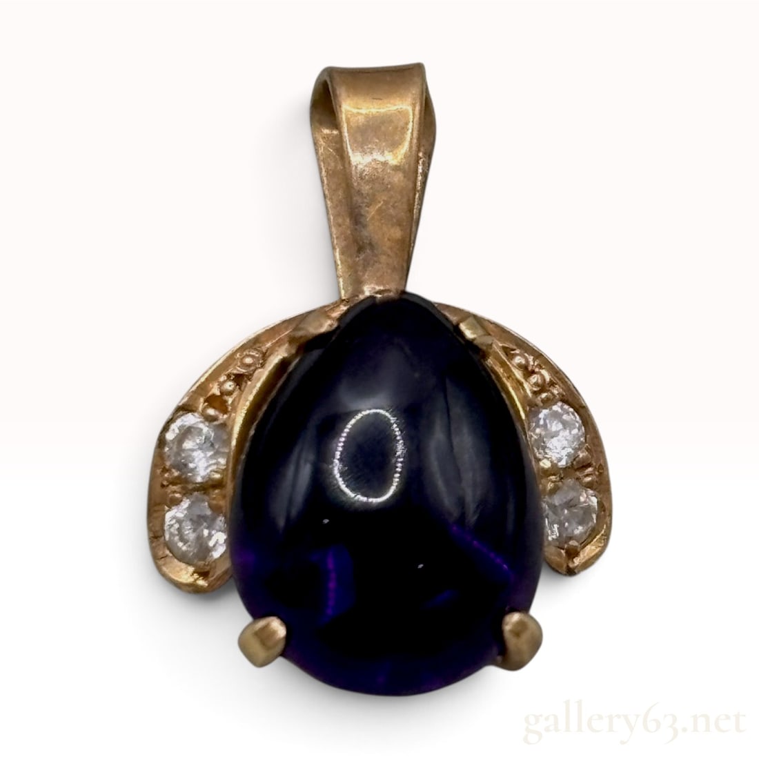 Vintage 14K Yellow Gold Amethyst and Natural Diamond Pendant: This vintage pendant is crafted from 14K yellow gold and features a central pear-shaped cabochon-cut amethyst. The gemstone is a deep, saturated purple hue, secured within a multi-pronged setting. The