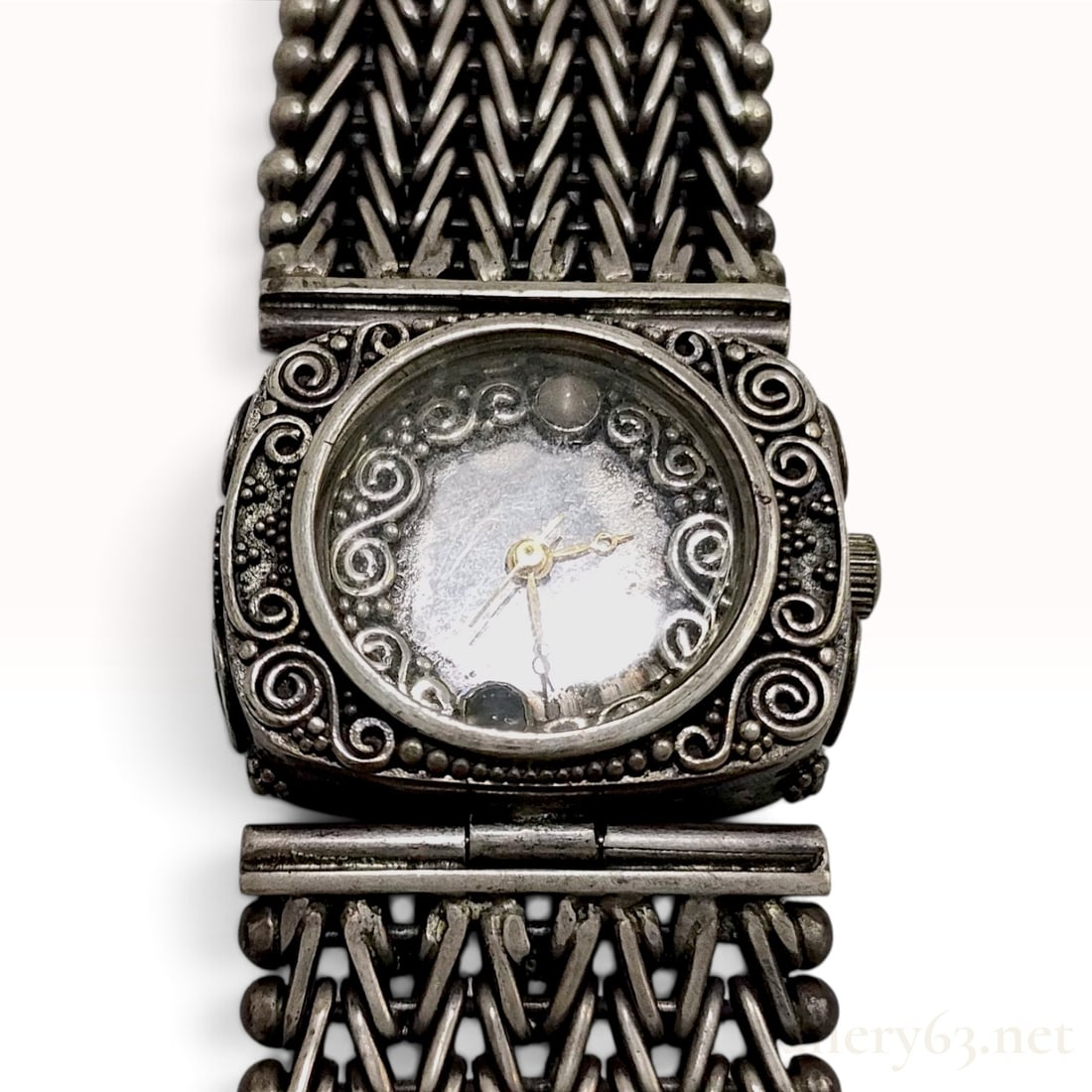 Vintage Hyboto Sterling Silver Ornate Woven Bracelet Watch: This vintage Hyboto jewelry watch is crafted from sterling silver. The timepiece features a square case decorated with elaborate scrollwork and filigree, housing a circular silver-tone dial with a mat