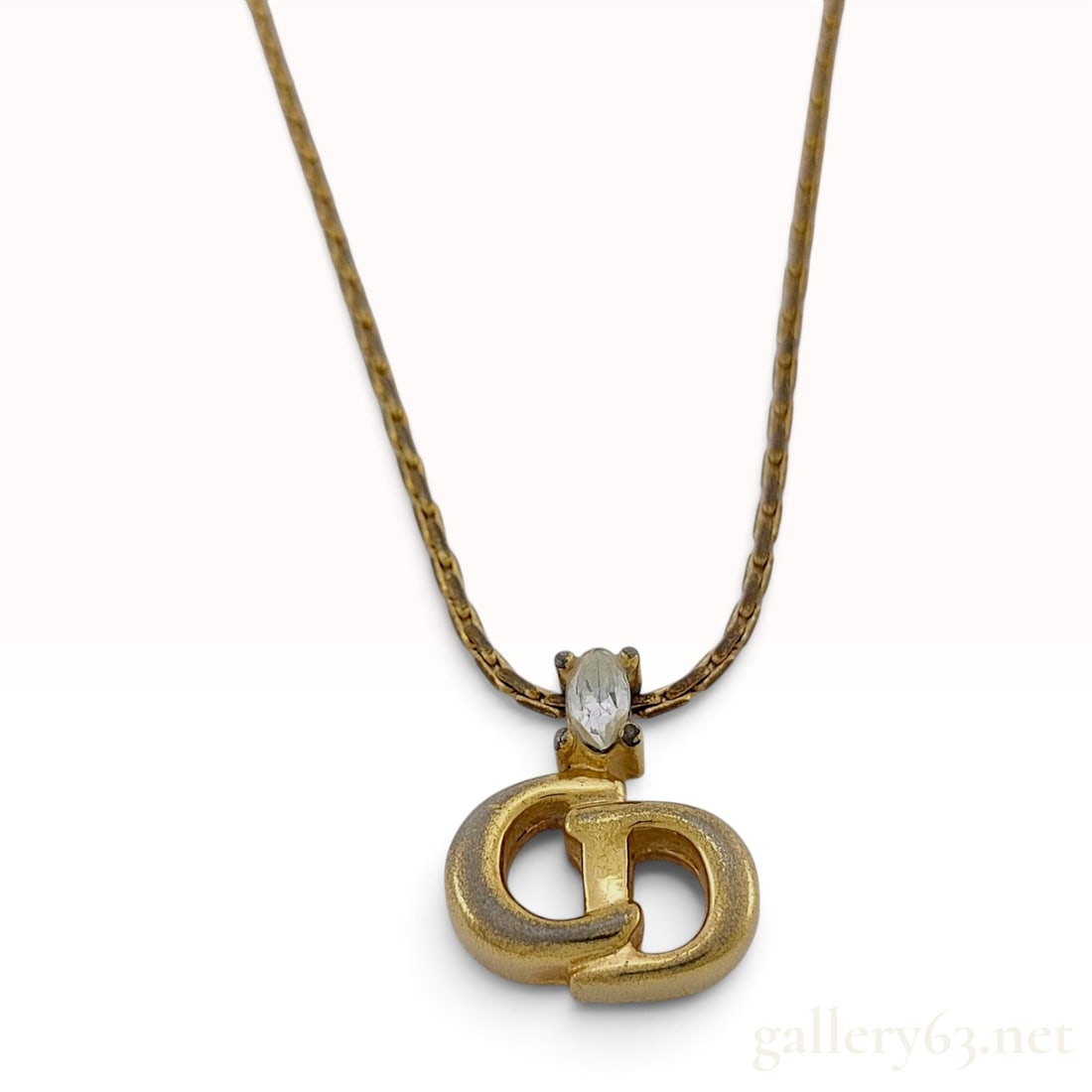 Vintage Christian Dior CD Logo Gold Plated Rhinestone Pendant Necklace: This Christian Dior pendant necklace is crafted from a gold-plated base metal featuring a fine curb link chain. The center of the piece is a fixed pendant designed in the signature interlocking CD log