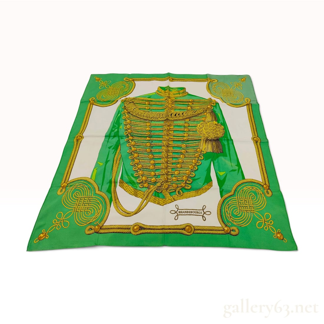 Vintage Hermes Brandebourgs Green Silk Carre 90: This Hermes silk carre 90 crafted from silk twill features the Brandebourgs pattern. The central motif depicts an elaborate military dolman jacket in vibrant green with intricate gold-toned frogging, 