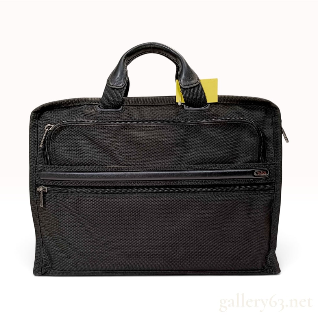 Tumi Black Ballistic Nylon Slim Business Briefcase: This Tumi business briefcase is crafted from durable black ballistic nylon with leather handles and trim. The slim profile design features multiple exterior zippered compartments for organization and 