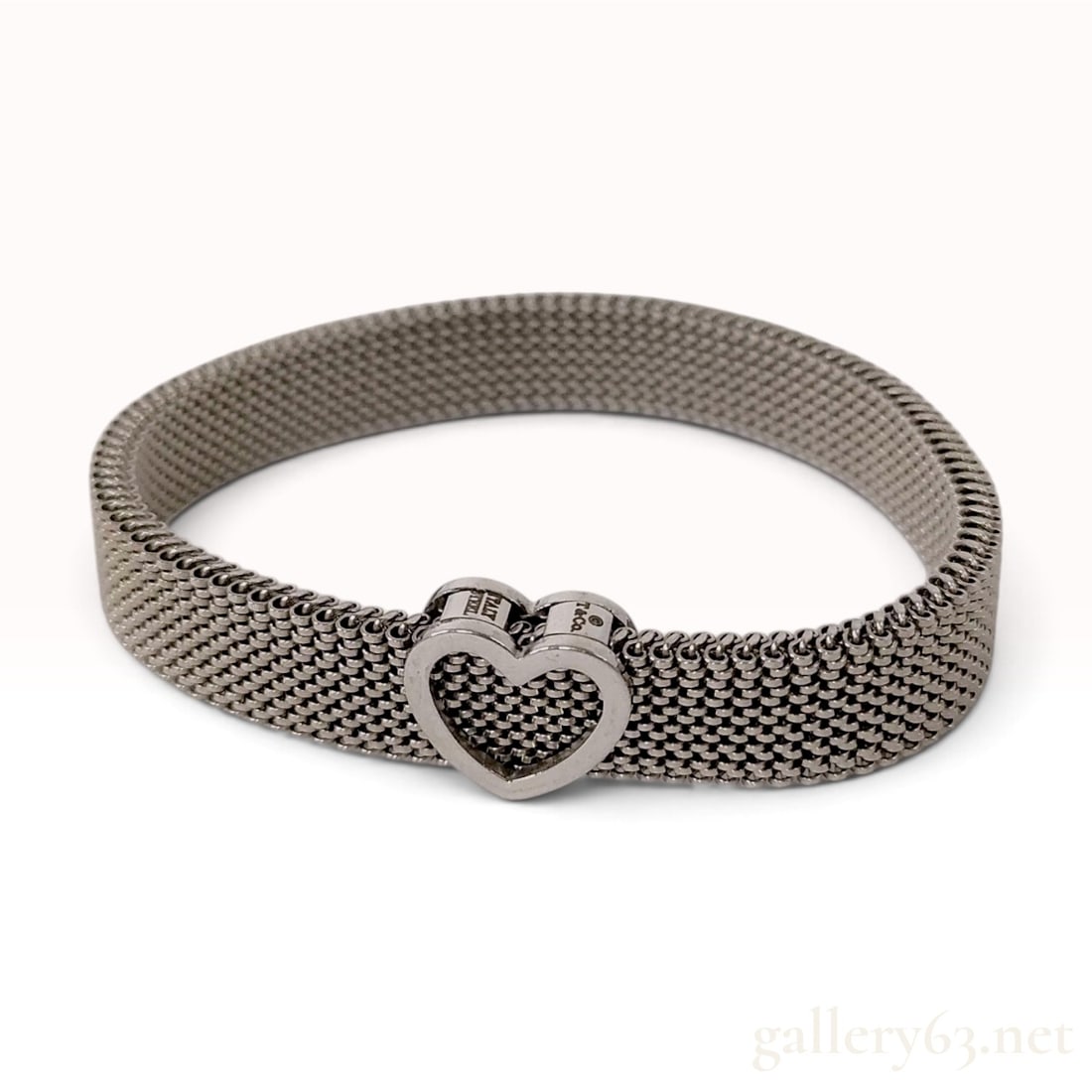 Tiffany and Co. Somerset Stainless Steel Mesh Heart Bracelet 16 cm: This is a Tiffany and Co. mesh band bracelet from the Somerset collection crafted from stainless steel. The design features a flexible mesh-weave band leading to a central integrated heart-shaped hing