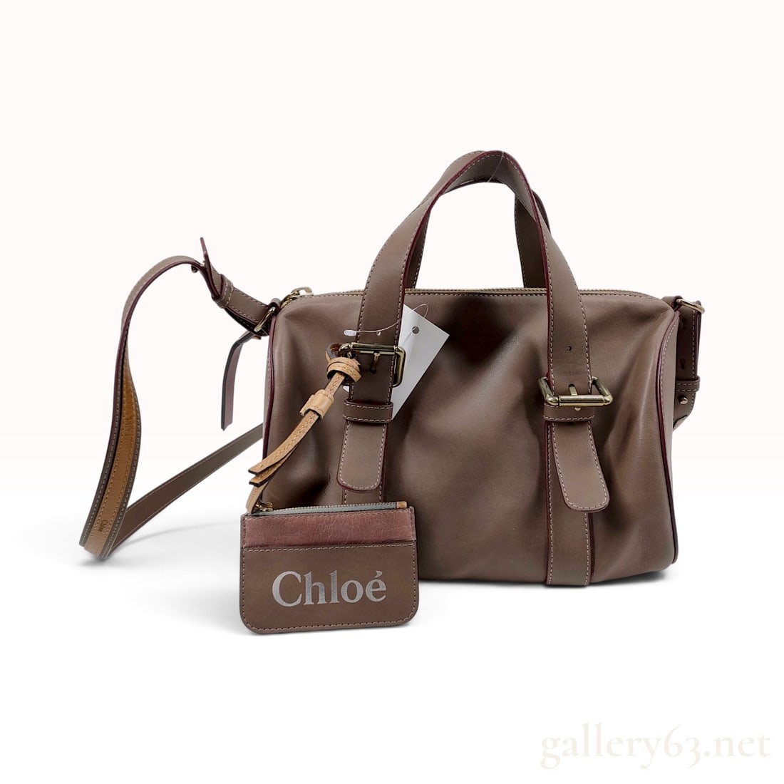 Chloe Taupe Calfskin Leather Bowling Bag with Accessory Pouch: This Chloe handbag is crafted from smooth taupe calfskin leather in a structured bowling bag silhouette. The exterior features dark burgundy edge glazing and decorative adjustable buckle straps on the