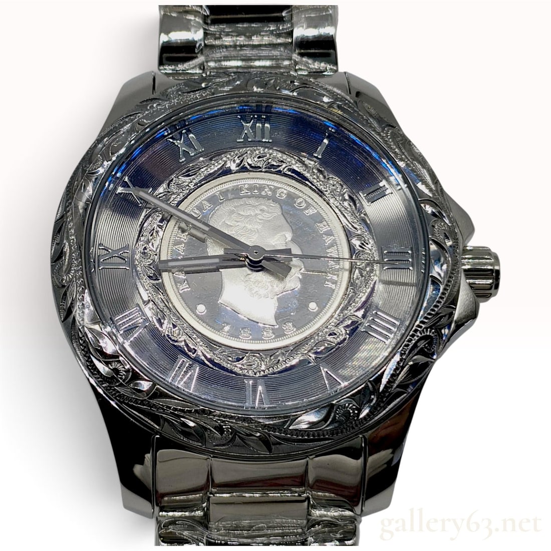 NWT K. Maui Stainless Steel Hawaiian Heirloom Kalakaua I Coin Dial Wristwatch: This K. Maui wristwatch is crafted from stainless steel with a high-polish finish and traditional Hawaiian Heirloom engraving. The bezel and lugs feature elaborate scroll and plumeria motifs. The dial