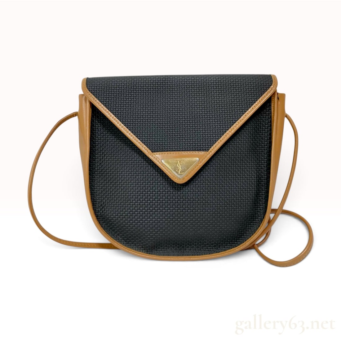 Vintage Yves Saint Laurent Black Textured and Tan Leather Saddle Crossbody Bag: A vintage Yves Saint Laurent saddle-style crossbody bag crafted from a textured black synthetic material with tan leather trim. The bag features a rounded silhouette with a triangular front flap secur