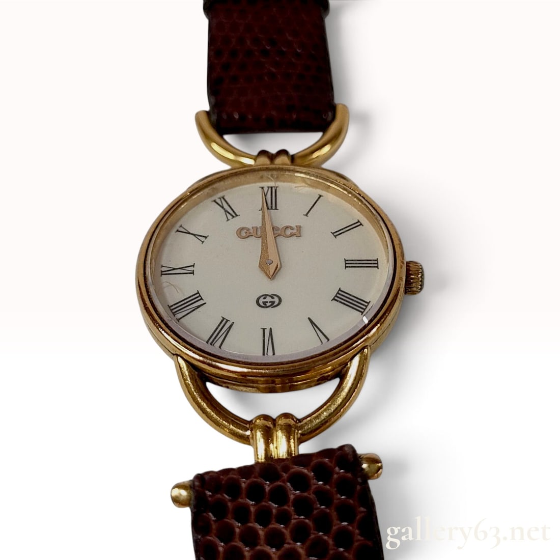 Vintage Gucci 6000L Gold Plated Ladies Wristwatch: A vintage Gucci 6000L ladies wristwatch featuring a circular gold-plated stainless steel case with distinctive arched lugs. The watch is fitted with an ivory dial featuring black Roman numeral hour ma