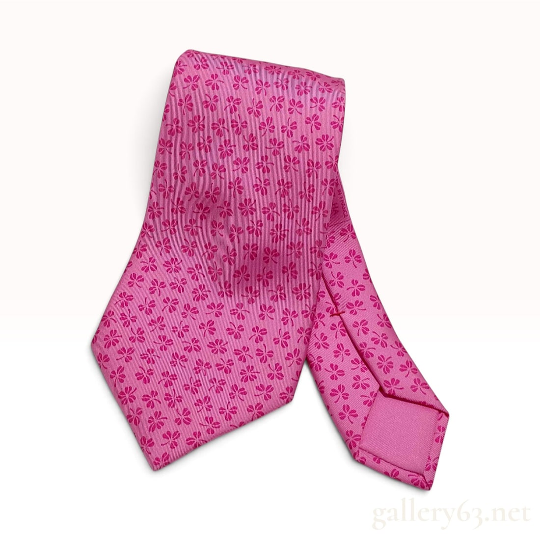 Hermes 5137 HA Pink Silk Clover Pattern Necktie: This Hermes necktie is crafted from 100% silk in a bright pink colorway. The design consists of an allover repeating pattern of small dark pink four-leaf clovers or shamrocks. The fabric features a fi