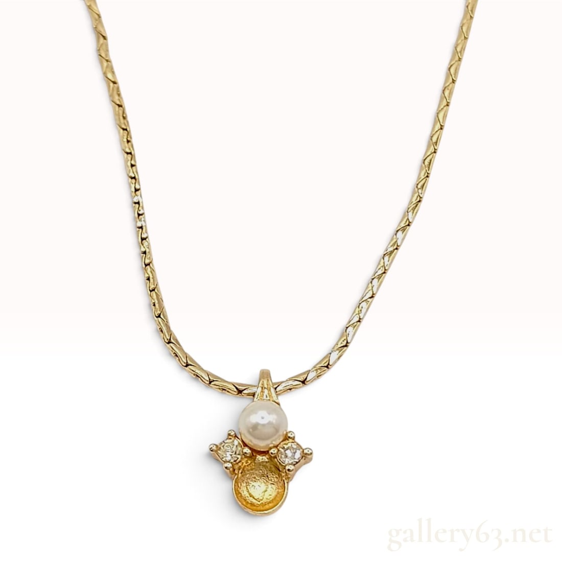 Vintage Christian Dior Faux Pearl and Crystal Pendant Necklace: This vintage Christian Dior pendant necklace is crafted from gold-tone base metal and features a stylized cluster-style pendant. The pendant design centers on a 6mm cream-colored faux pearl flanked by