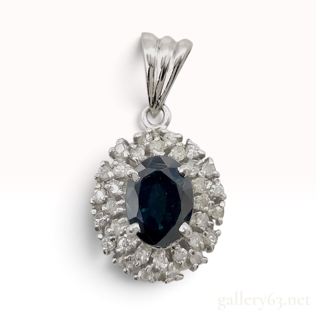 Platinum 1.01ct Sapphire and 0.18ctw Natural Diamond Halo Pendant: This platinum pendant features a central oval-cut sapphire of a deep navy blue hue, secured in a four double-prong setting. The center stone is surrounded by a two-tiered halo of round-cut natural dia