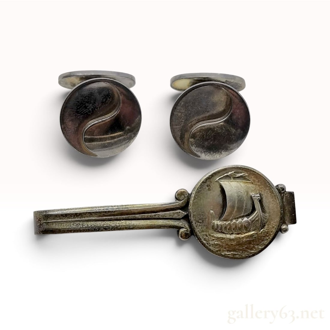 Vintage Georg Jensen Viking Ship Sterling Silver Tie Clip and Cufflinks Trio: This Georg Jensen jewelry collection is crafted from sterling silver and consists of a tie clip and a pair of cufflinks. The tie clip, identified by design number 50, features a circular medallion wit
