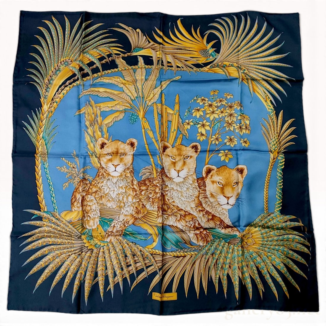 Salvatore Ferragamo Lion Cub Motif Navy and Light Blue Silk Scarf 90 cm with Box: This Salvatore Ferragamo silk scarf 90 cm is crafted from 100% silk and decorated with a central motif of three lion cubs featuring stylized fur rendered in leaf-like patterns. The cubs are positioned