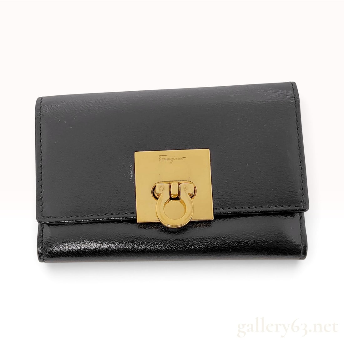 Salvatore Ferragamo Gancini Black Leather 6-Ring Key Case: This Salvatore Ferragamo key case is crafted from black leather with a bi-fold construction. The front features a square gold-tone plate mounted with a swivel Gancini clasp, which is engraved with the