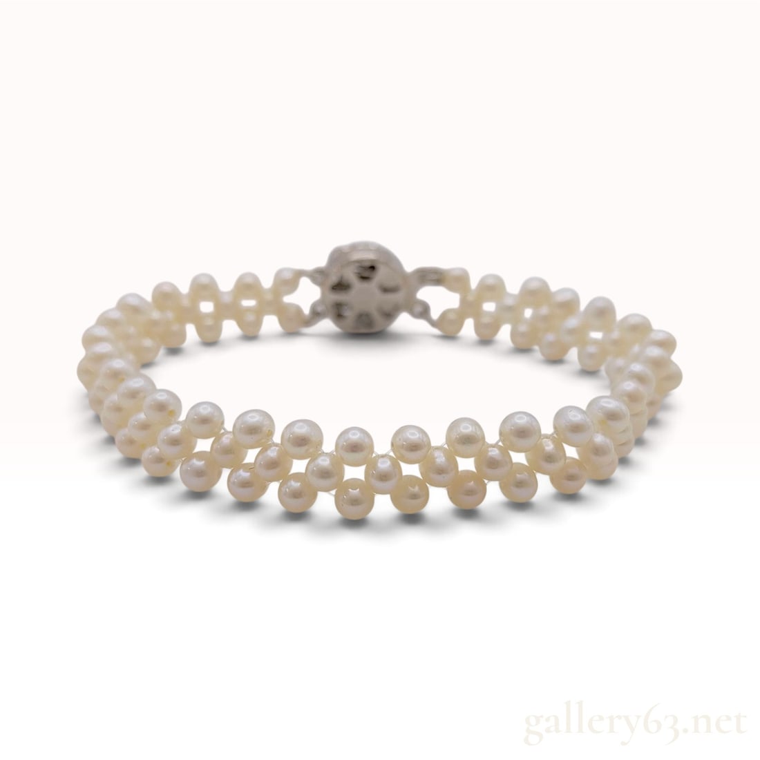 A Vintage Silver Triple-Strand Woven Pearl Bracelet: This vintage bracelet is crafted from silver and features a triple-strand woven design composed of numerous cream-white pearls. The small pearls are arranged in a decorative lattice pattern, providing