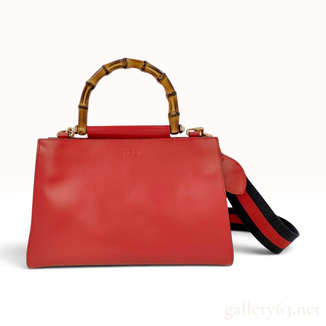 Gucci Small Hibiscus Red Leather Nymphaea Bamboo Top Handle Bag: This Gucci Small Nymphaea handbag is crafted from hibiscus red smooth leather in a structured trapezoidal form. The bag features a natural curved bamboo top handle accented by cream-colored resin pear