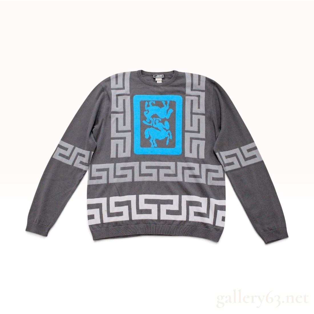 Vintage Gianni Versace Greek Key Centaur Motif Grey Knit Sweater: This Gianni Versace long-sleeve crewneck sweater is crafted from a charcoal grey knit material. The front center features a bright blue rectangular field containing two opposing centaur figures in a d