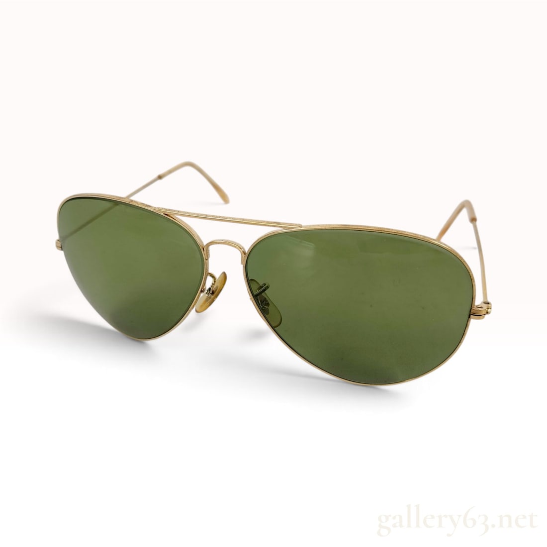 Vintage Bausch & Lomb Ray-Ban Aviator Sunglasses in Gold and Green: This pair of vintage Bausch & Lomb Ray-Ban aviator sunglasses is crafted with gold-toned metal frames and classic green glass lenses. The frame features the iconic teardrop lens silhouette with a doub
