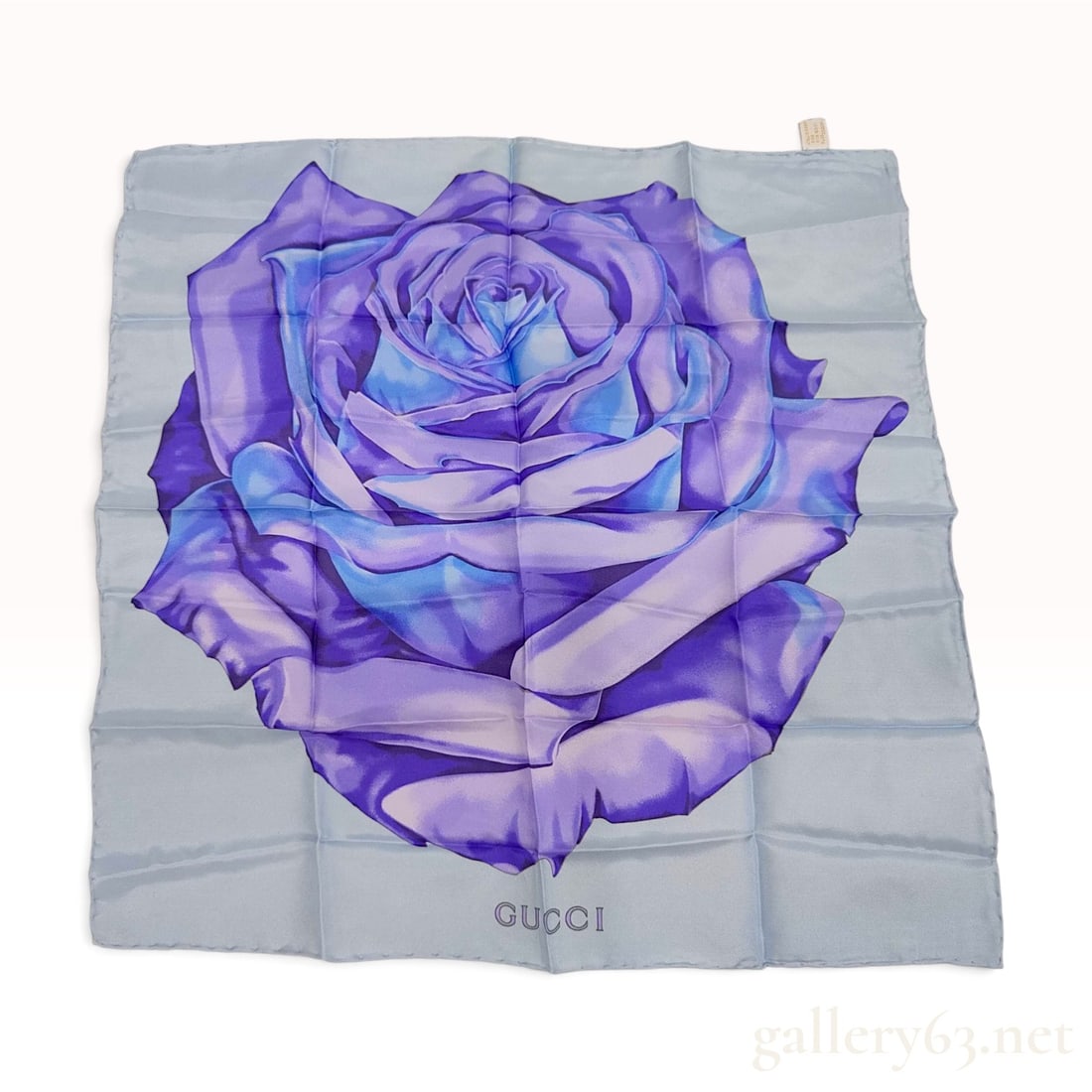 Vintage Gucci Purple Rose Silk Carre 45: This is a Gucci silk carre 45 featuring a large-scale graphic print of a multi-petaled rose. The floral motif is rendered in shades of purple, violet, and blue, centered against a pale blue ground. Th