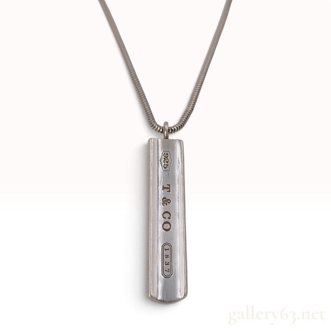 Tiffany & Co. 1837 Sterling Silver Bar Pendant Necklace with Box and Pouch: A Tiffany & Co. pendant necklace from the 1837 collection crafted from sterling silver. The necklace features a rectangular bar pendant with a slightly concave face and rounded ends, suspended from a 