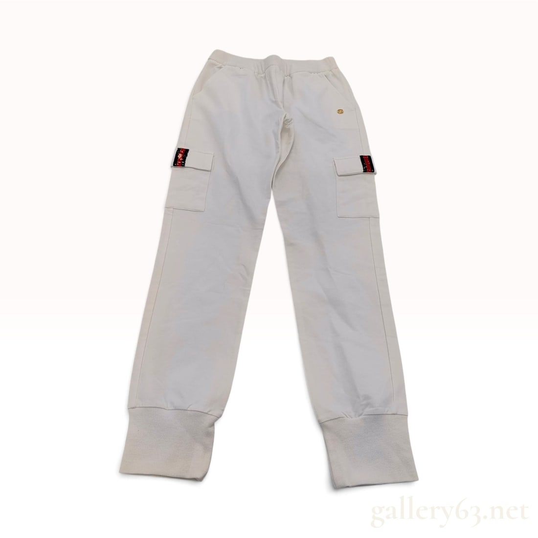 Gucci Off-White Cotton Sequined Cargo Joggers Size 10: This pair of Gucci children's cargo joggers is crafted from an off-white cotton French terry knit. The garment features an elasticized waistband and two patch cargo pockets positioned at the outer thi