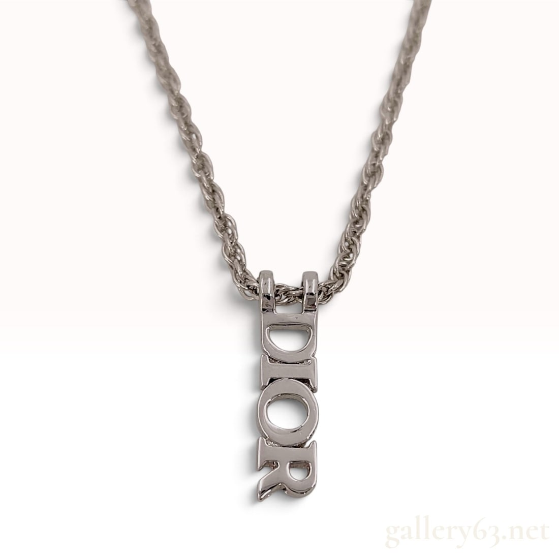 Vintage Christian Dior Logo Pendant Rope Chain Necklace: This vintage Christian Dior necklace is crafted from silver plated metal featuring a prominent vertical block letter pendant spelling DIOR. The pendant is suspended from a rope chain that transitions 