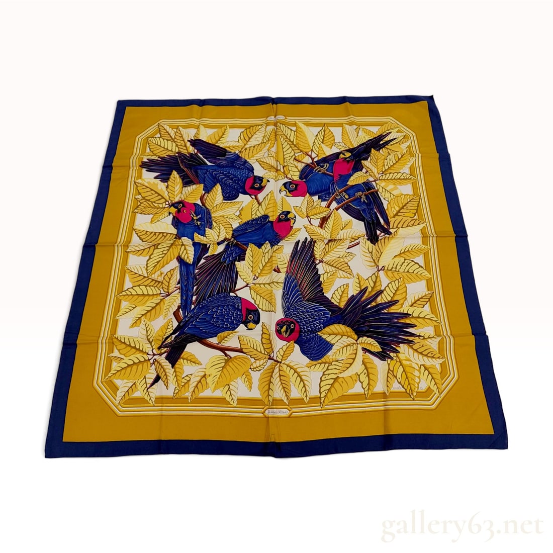Vintage Hermes Les Perroquets Silk Carre 90 in Yellow and Blue: This Hermes silk carre 90 features the Les Perroquets pattern designed by Joachim Metz. The design depicts vibrant blue parrots with pink-red heads and yellow beaks, perched among stylized yellow and 