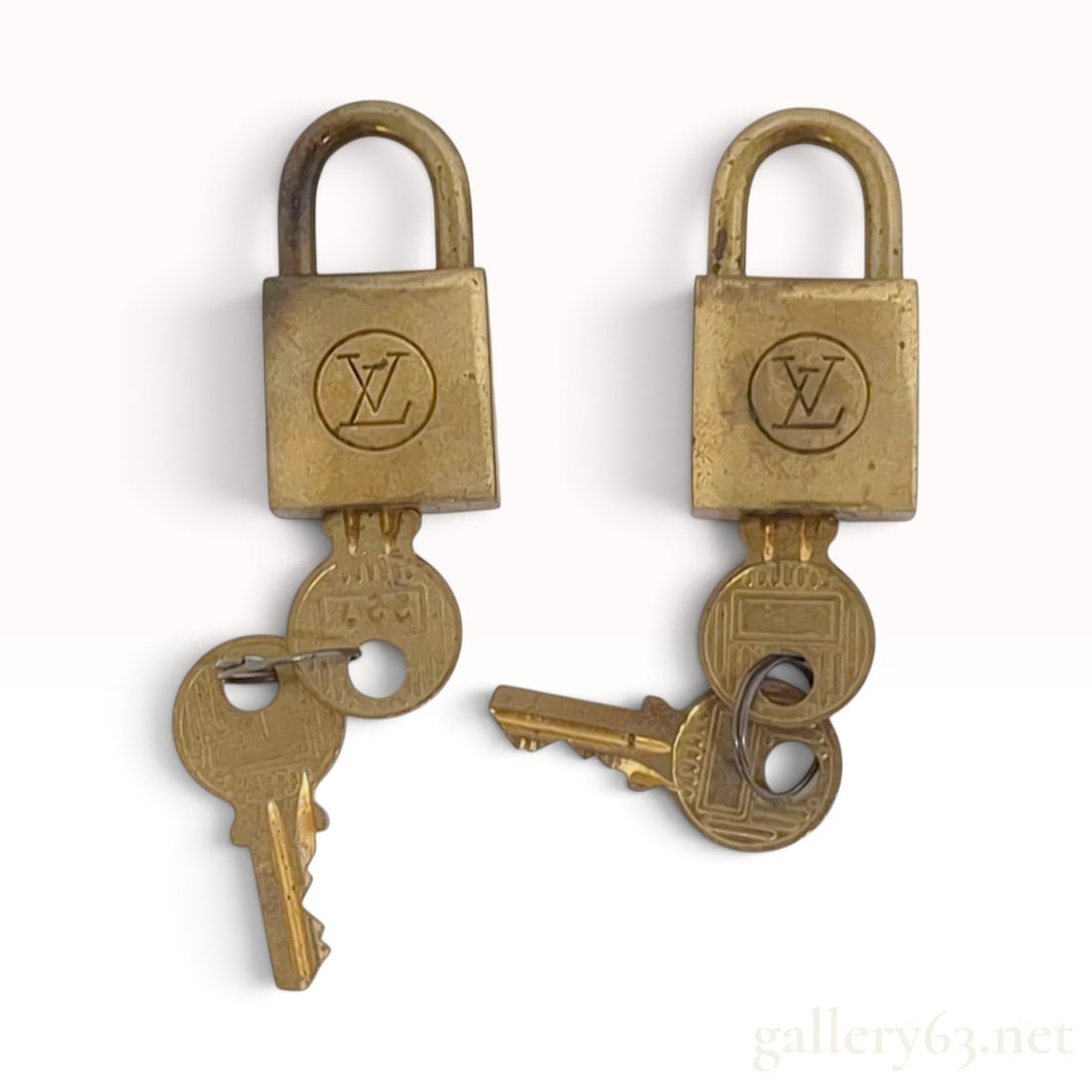 Vintage Louis Vuitton Brass Padlocks with Keys: A pair of vintage Louis Vuitton luggage padlocks crafted from solid brass. Each padlock features a rectangular body and a matching pair of keys on a small metal split ring. The front faces are impress