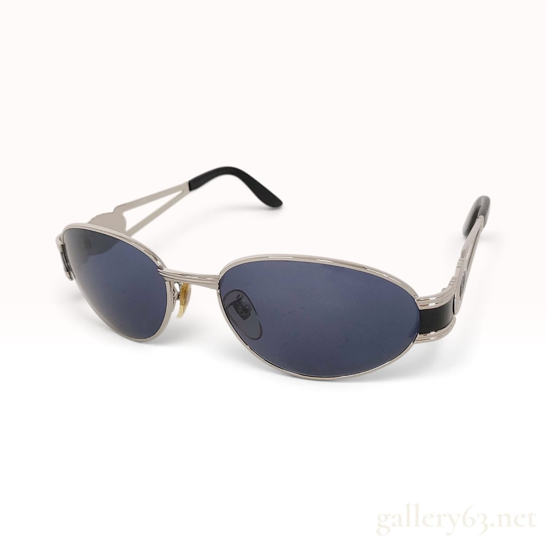 Vintage Fendi SL 7055 Silver Metal Oval Sunglasses: This pair of Fendi sunglasses is crafted from silver metal with blue-gray tinted lenses. The frames feature an oval-wrap silhouette and distinctive split-arm temples with a central cutout design. Each