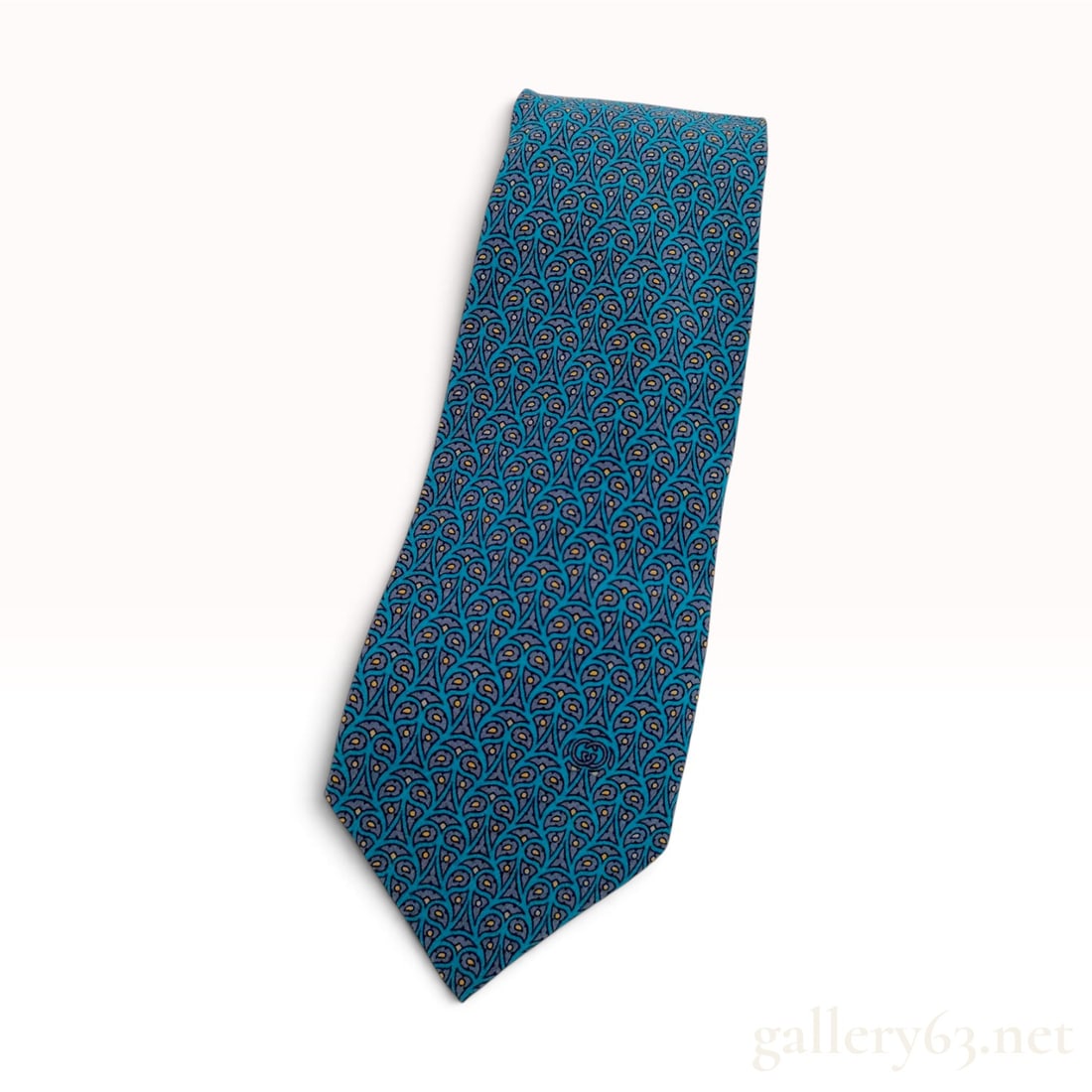 Vintage Gucci Accessory Collection Teal and Gray Silk Necktie with Tag: This Gucci necktie is crafted from 100% Italian silk. The design features a stylized, repeating teardrop or paisley-like motif in teal blue and charcoal gray, accented with small gold-tone dots. The b