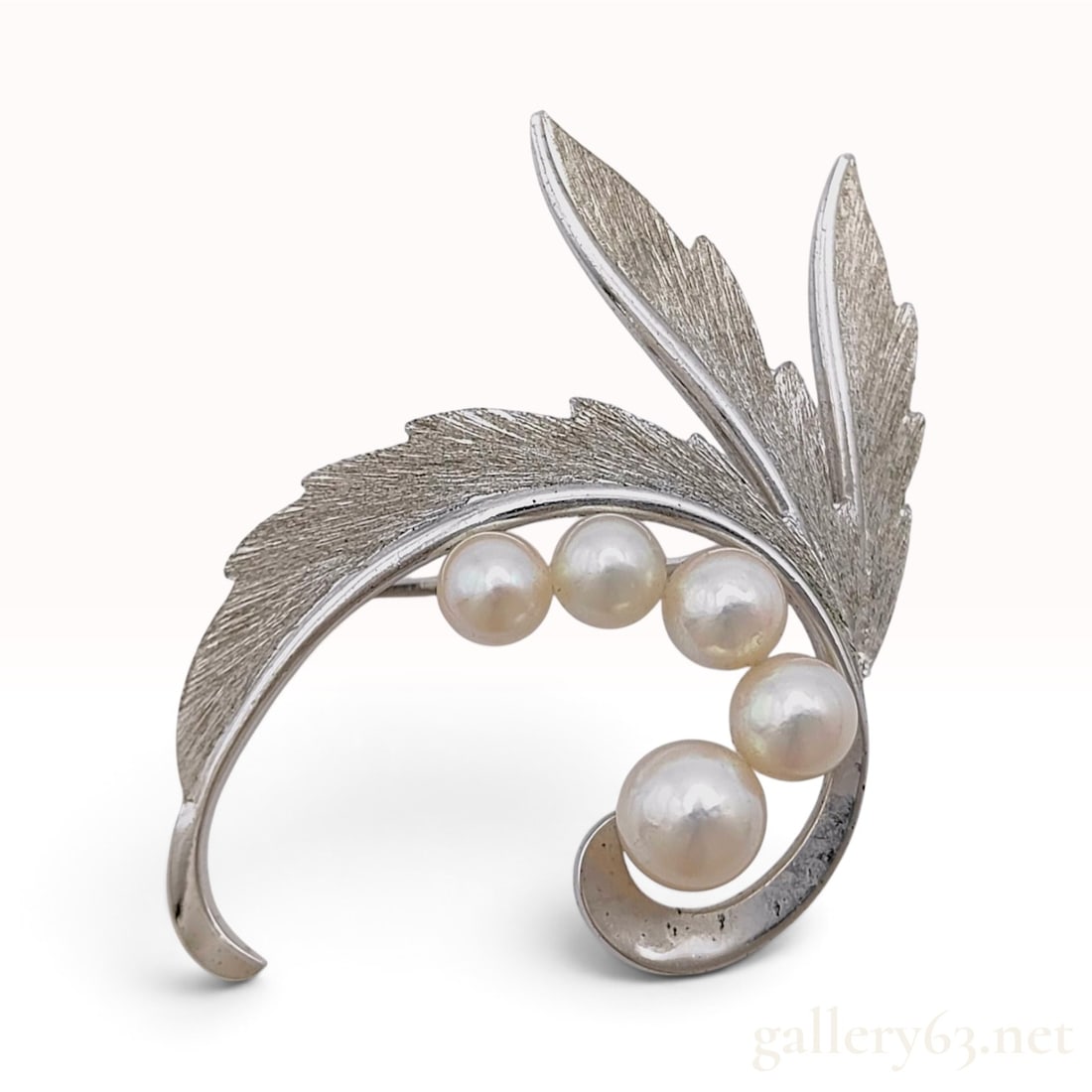 Vintage Sterling Silver and Graduated Cultured Pearl Foliate Brooch: This vintage foliate brooch features a stylized leaf motif with a textured, brushed finish on the front surface. The curved design is set with five graduated white cultured pearls that exhibit high lu