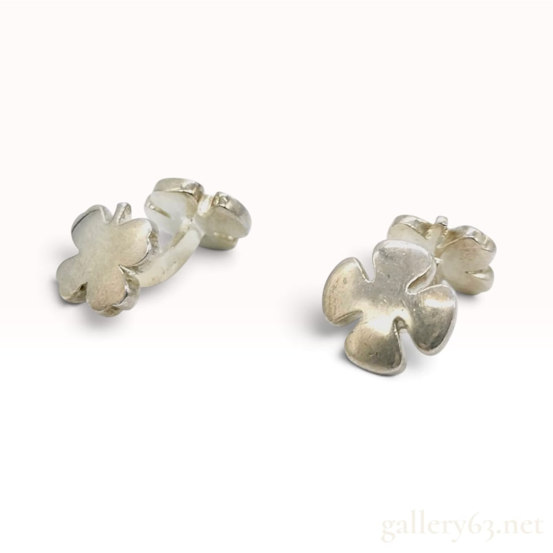 Vintage Chanel Four-Leaf Clover Silver Cufflinks: This pair of vintage Chanel cufflinks is crafted from silver featuring a double four-leaf clover design joined by a fixed curved bridge. The clover motifs are rendered with a rounded, three-dimensiona