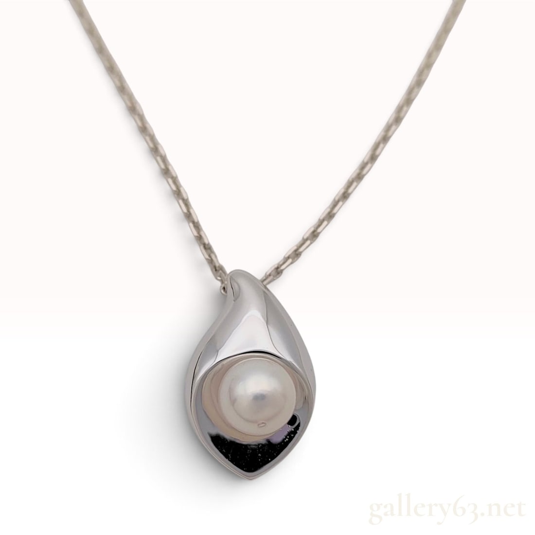 Sterling Silver and Cultured Pearl Petal Pendant Necklace: This is a sterling silver pendant necklace featuring a stylized petal-shaped pendant. The polished silver pendant is designed with a deep curve that cradles a single white cultured pearl. The pearl me
