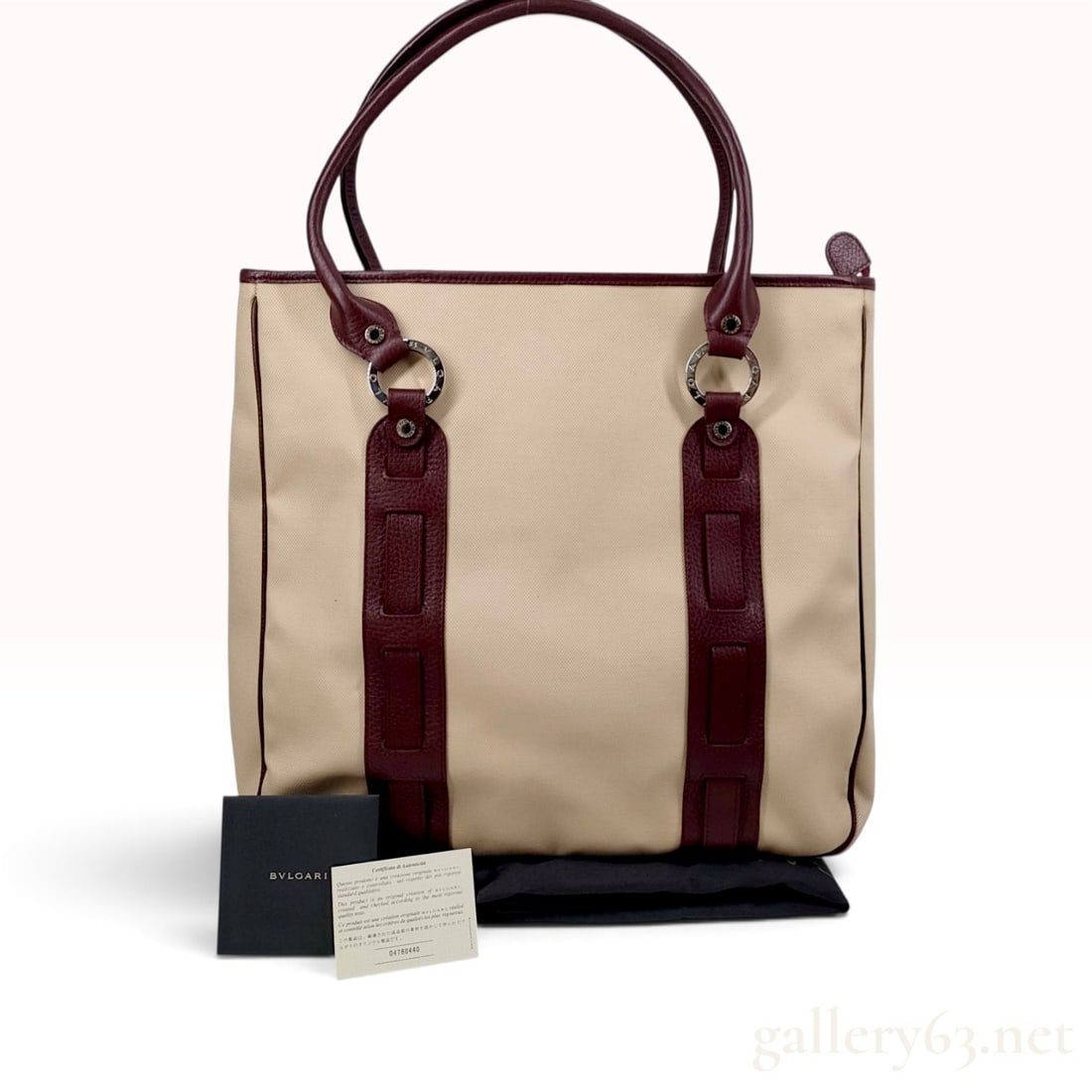 Bulgari Beige Canvas and Burgundy Leather Tote Bag with Certificate: This Bulgari tote bag is constructed from beige canvas with burgundy pebbled leather handles, trim, and vertical decorative straps. The bag features a top zipper closure with a matching burgundy leath