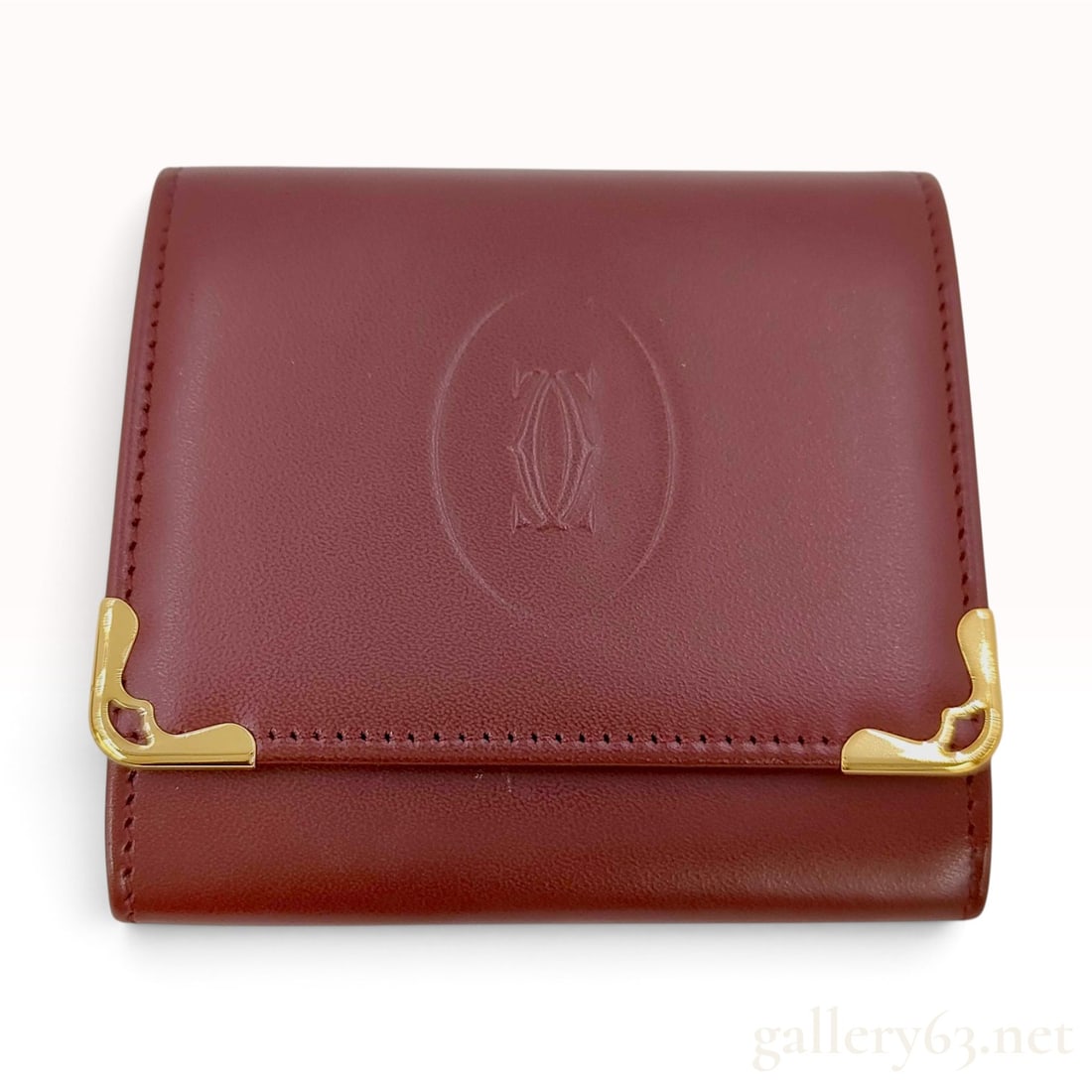 Vintage Cartier Must de Cartier Burgundy Leather Coin Purse: This Cartier Must de Cartier coin purse is crafted from smooth burgundy leather. The front flap features a large embossed interlocking double C logo within an oval border, accented by two gold-tone me